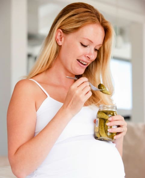 pregnant woman with pregnancy cravings eating pickles