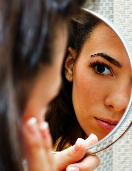 woman looking at her appearance in mirror