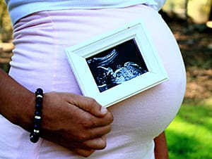 woman wonder how is my baby growing and holding photo of her baby's fetal development