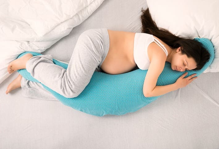 Woman snuggles a pregnancy pillow