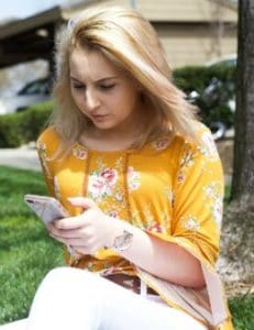 Girl browses phone outside