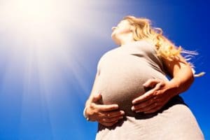 Woman in third trimester looks up at sun