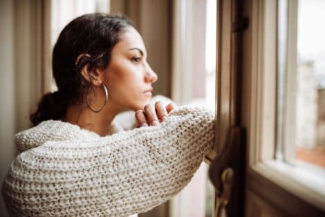 Woman looks out the window, deep in thought worried about the plan b pill option she heard about