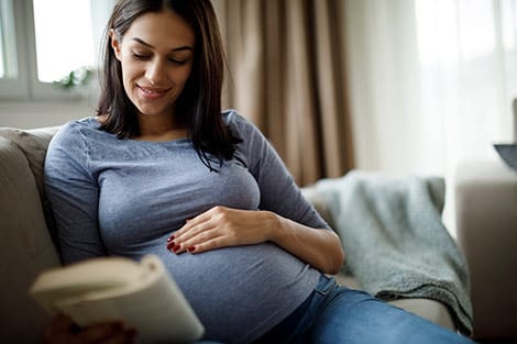Pregnant woman reading a pregnancy book at home