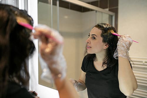 Woman applying hair color in her bathroom
