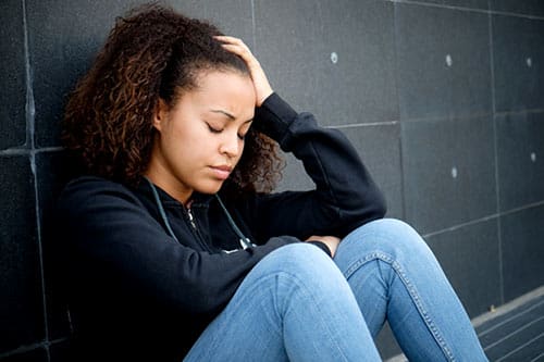 A young, stressed-out woman seated, wondering, 'am I pregnant?'