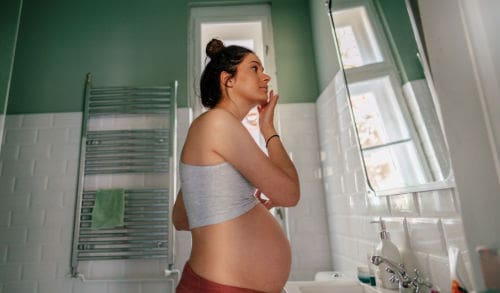 Expectant mother applying pregnancy-safe skincare products in her bathroom