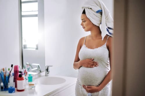 Pregnancy help for a woman in her bathroom after a shower, wondering about pregnancy-safe shampoos