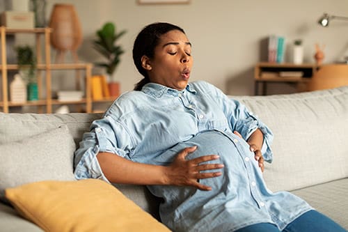 African American pregnant woman touching her belly, suffering painful contractions