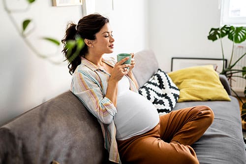Woman peacefully enjoys a cup of coffee after reading how much caffeine is safe during pregnancy