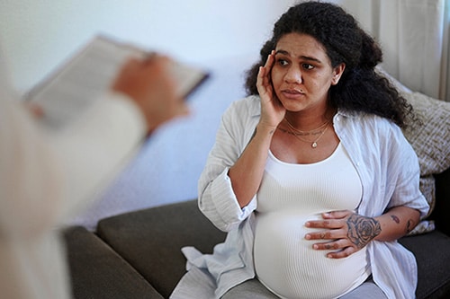 Worried and depressed woman talks with her doctor at a prenatal appointment
